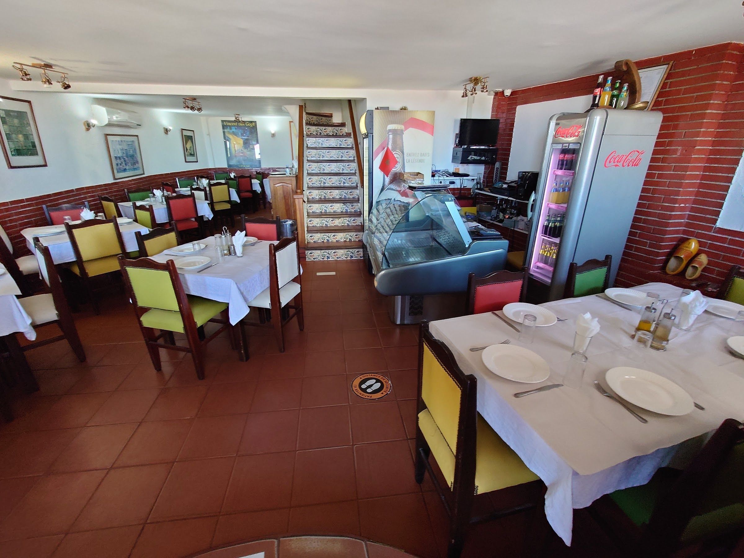 La salle : nappes blanches, chaises jaunes et vertes, vitrine à poissons