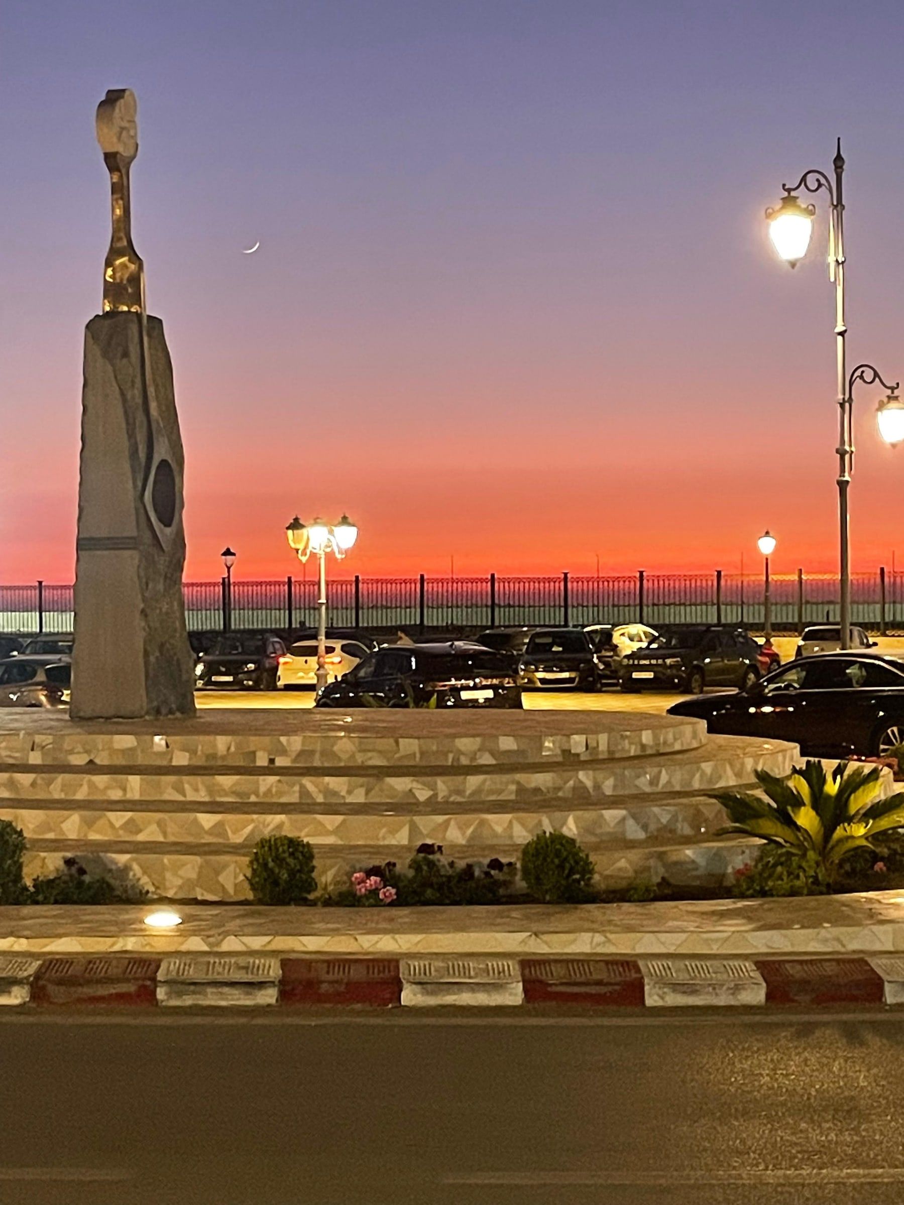 Coucher de soleil depuis la terrasse de La Place, au-dessus du rond-point et de la sculpture d’Asilah