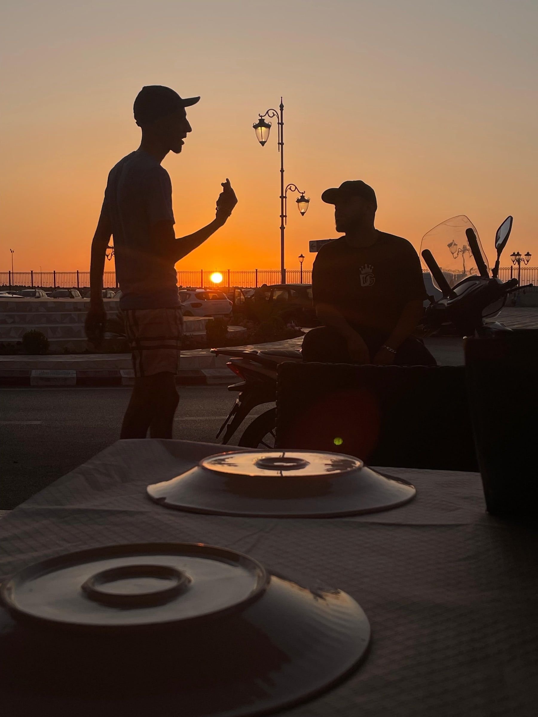 Deux silhouettes devant le soleil couchant, vues depuis une table de la terrasse